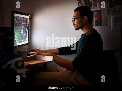 Working on a new game. a young programmer focused on his work. Stock Photo