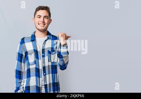 Cheerful guy with friendly smile pointing to the side isolated. Smiling young man pointing with one hand a promotion to the side. Concept of handsome Stock Photo