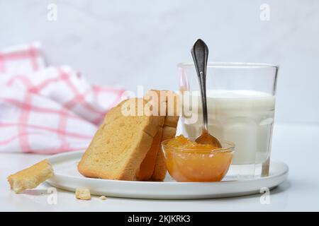 Rusk, glass of milk and orange marmalade in small bowls Stock Photo