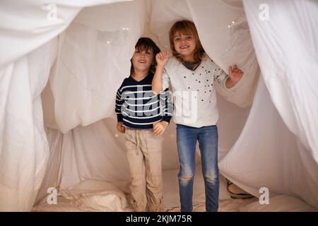 Fun in the fort. Portrait of two adorable siblings jumping on the mattress underneath their fort. Stock Photo