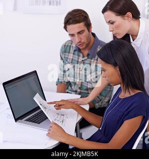 Discussing the finer details. a group of young architects working together in the office. Stock Photo