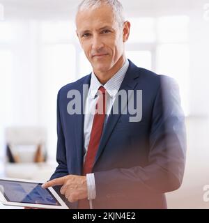 Getting work done on my tablet. a mature businessman looking content and pointing at his tablet. Stock Photo