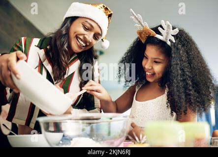 Christmas, love and girl baking with mother in kitchen to make festive cookies, biscuits and treats. Black family, love and mom bake with child Stock Photo