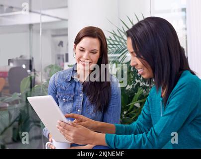 Youve got to check this out. two coworkers using a digital tablet in a discussion. Stock Photo