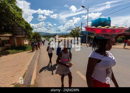 Street vendor girls walking on a street with fruit baskets on their heads Stock Photo