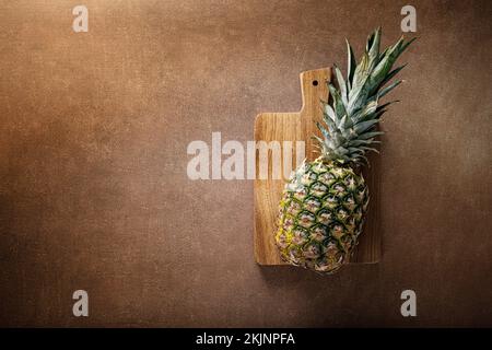 Pineapple. Whole pineapple on brown background, top vew Stock Photo