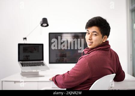 His IT expertise will live up to your expectations. Portrait of a young man sitting at his computer desk. Stock Photo