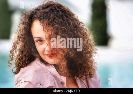 A beautiful hispanic woman with painted lips and curly hair looking at the camera Stock Photo