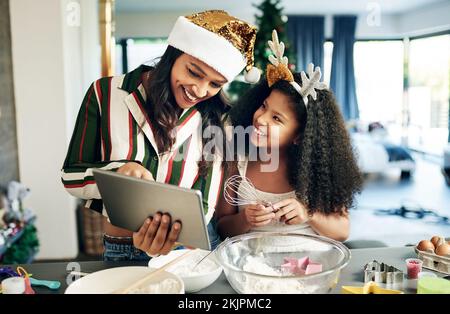 Family, baking and tablet for christmas cookies, cooking or cake with mother and daughter together while learning online recipe in kitchen, Black Stock Photo