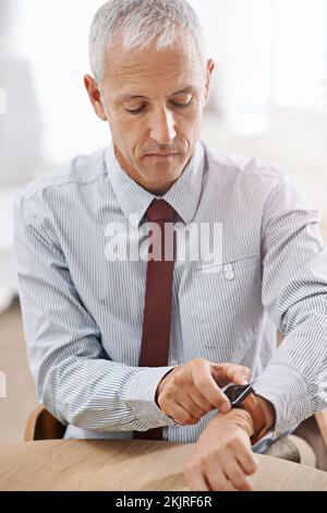 Its a smart watch for the modern businessman. a mature businessman using a smart watch. Stock Photo