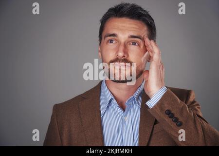 Hell come up with a solution. Studio shot of a man deep in thought against a gray background. Stock Photo
