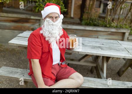 A Santa Claus at Christmas time in  the Australian summer holding a beer Stock Photo