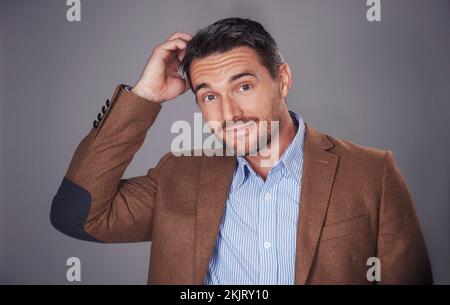 I did what now. Studio portrait of a man scratching his head against a gray background. Stock Photo