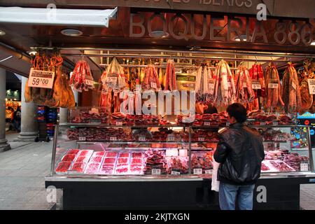 Barcelona, Spain - March 30, 2009: A customer at a butcher shop in the world famous, La Boqueria in Barcelona, Spain. Spain is renowned for cured and Stock Photo