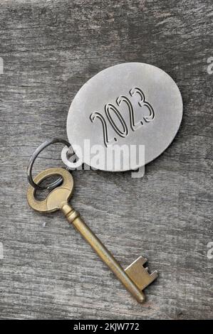 2023 engraved on a ring of an old golden key on rustic wooden Stock Photo