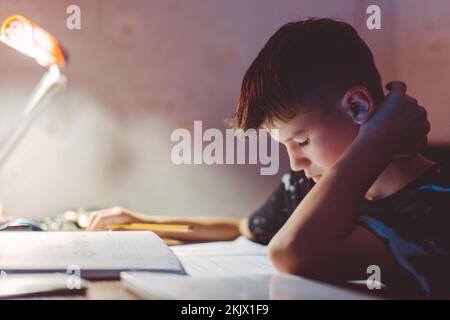Young Caucasian tired boy learning at evening Stock Photo