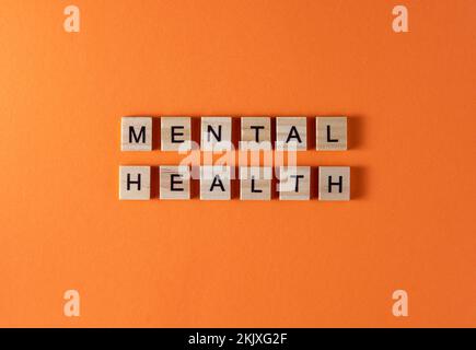 Mental health word phrase in wooden letters. Motivation and slogan. Orange background. Stock Photo