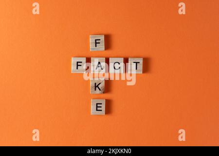 Fake fact word phrase in wooden letters. Motivation and slogan. Orange background. Stock Photo