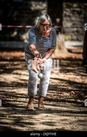 A player throws a ball, boule during a traditional french game of pétanque in the village square Stock Photo