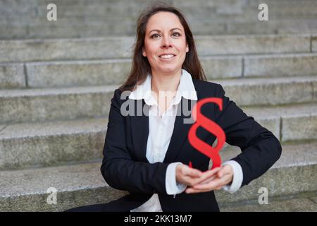 Happy female lawyer holding big red paragraph sign as justice and law symbol Stock Photo