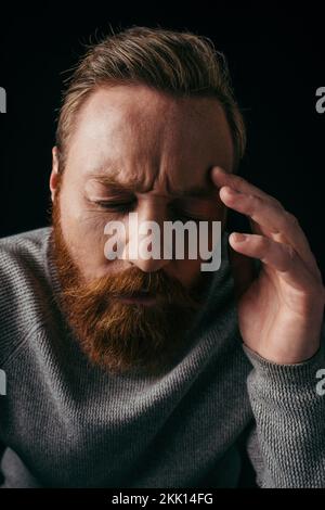 Portrait of worried man in long sleeve touching forehead isolated on black,stock image Stock Photo