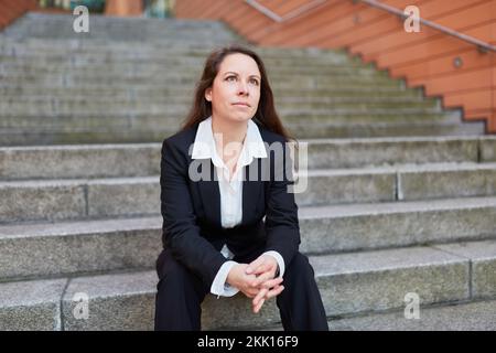 Female businesswoman sitting on stairs in urban city and waiting Stock Photo