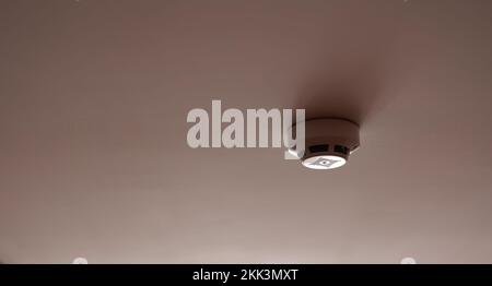 Fire system indoors. White smoke detector issue a signal to a fire alarm control panel as part of a fire alarm system installed on the white ceiling in the office building or apartment Stock Photo