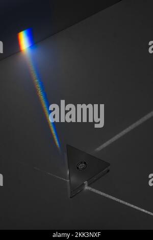 Dispersion of white light into colours of the spectrum as different wavelengths travel at different speeds in glass prism projected on paper screen Stock Photo