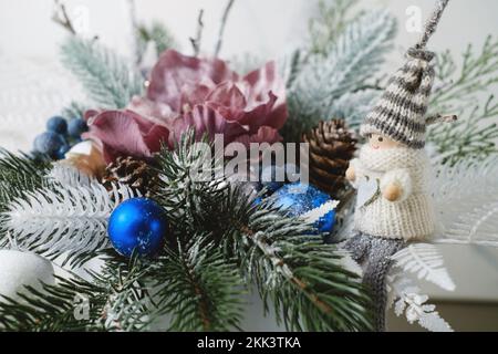 Christmas composition in box with spruce, fern for table decoration. Snowy bunches with blue bobbles, elf in beautiful packaging, assembled by a Stock Photo