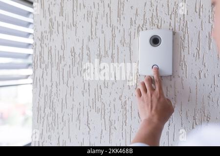 Close-up photo. The finger of a man's hand presses the button of the incoming call of the door, the camera. Electric lock to office, home, delivery. Stock Photo