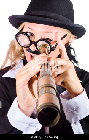 Businesswoman in bowler hat and dark suit with thick rimmed glasses, fake mustache looking through antique telescope Stock Photo