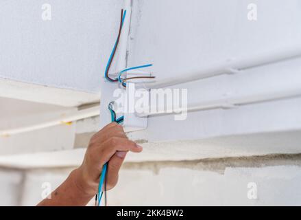 Close up electrician hand pulling wire into PVC Conduit. install new electric system. Stock Photo