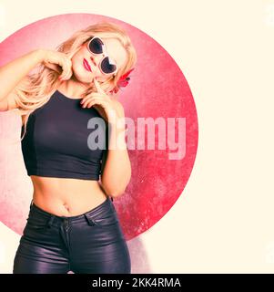 Old fashion photo of a beautiful smiling blond pin up woman dressed in 1950s clothing with leather pants and black tank top tilting head sideways with Stock Photo