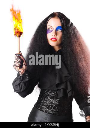 Woman in black medieval costume with face paint and burning fire torch, white background Stock Photo