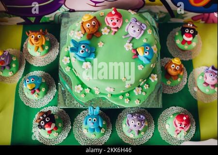 festive children's table with a beautiful cake decorated with green and multi-colored biscuits. candy. Children's birthday.Cake for children's Stock Photo