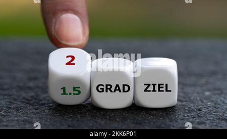 Hand turns dice and changes the German expression '1.5 Grad Ziel' (1.5 degree target) to '2 Grad Ziel' (2 degree target). Stock Photo