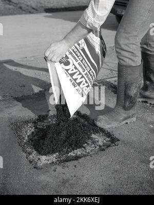 1980s, re-surfacing, a man using a bag of a new construction product to patch or repair a driveway, a ready-mix or ready to lay black tarmacmacadam or asphalt, known as a cold-lay tar, England, UK. Stock Photo