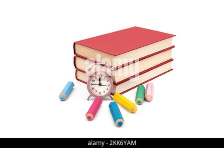 Classic pink table clock with red books and colorful eraser in shaped pencil on white background Stock Photo