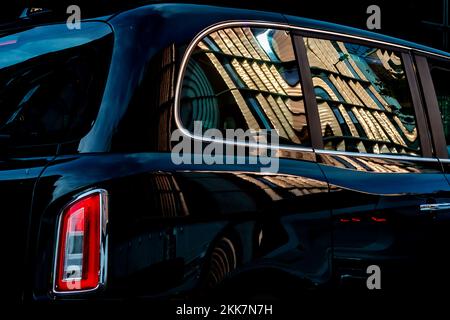 A new Black Taxi Cab with a shiny new building reflected in it's highly polished bodywork.This makes a compelling editorial image.Side view. Stock Photo