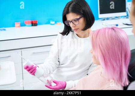 Dentist in the clinic introduces the patient to the irrigator Stock Photo