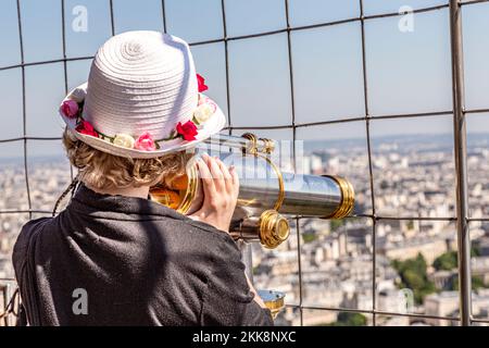 Paris, France - June 12, 2015: woman watching paris by telescope fromk platform at the eiffel tower.