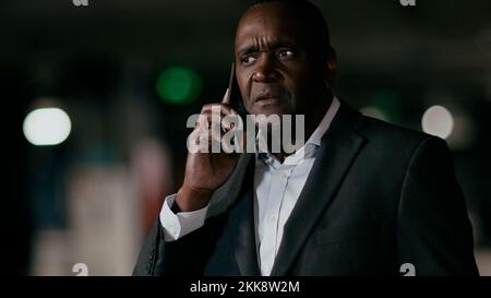 Serious puzzled excited emotional man talking on mobile phone adult worried african american businessman answering business call using smartphone Stock Photo