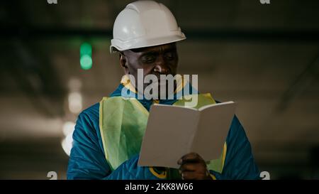 Mature man professional worker engineer builder with protective helmet inspects room writes data in notebook concentrated experienced foreman creates Stock Photo