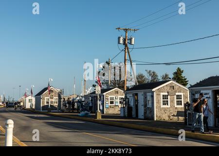 Provincetown, USA - September 24, 2017: people enjoy a warm summer day in the historic harbor with old fishermen huts in Provincetown, USA. Stock Photo