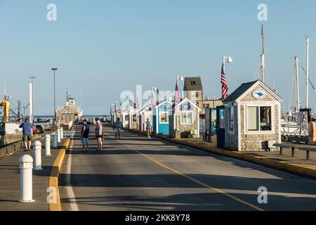 Provincetown, USA - September 24, 2017: people enjoy a warm summer day in the historic harbor with old fishermen huts in Provincetown, USA. Stock Photo