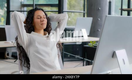 Young attractive hispanic woman office manager businesswoman typing on computer carefree female professional worker finishes work leans back on back Stock Photo