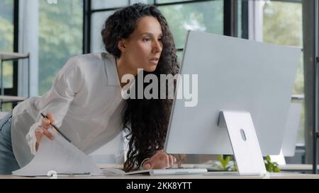 Young attractive hispanic woman professional manager developer working in modern office focused businesswoman checking electronic information on Stock Photo