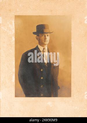 Antique sepia tone photo of a distinguished looking young man wearing a suit and hat. Stock Photo