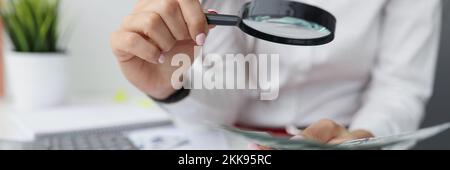 Female hold magnifying glass analyzing business financial data, manager calculates company finances Stock Photo