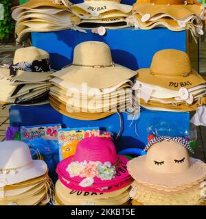 Colorful trendy female summer sun straw hats for sale in beach shop in Dubai. Assortment hats stacked in rows.Summer vacation,Dubai,UAE,Nov 2022 Stock Photo